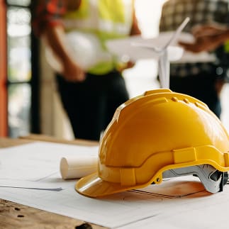 Yellow hard hat on architectural blueprints
