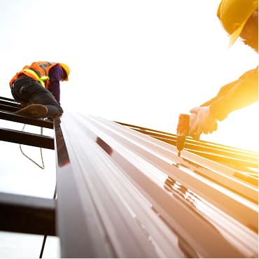 Workers installing a metal roof in bright sunlight
