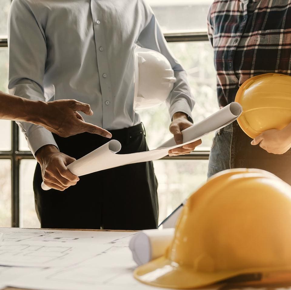 Two construction professionals reviewing architectural blueprints at a work table