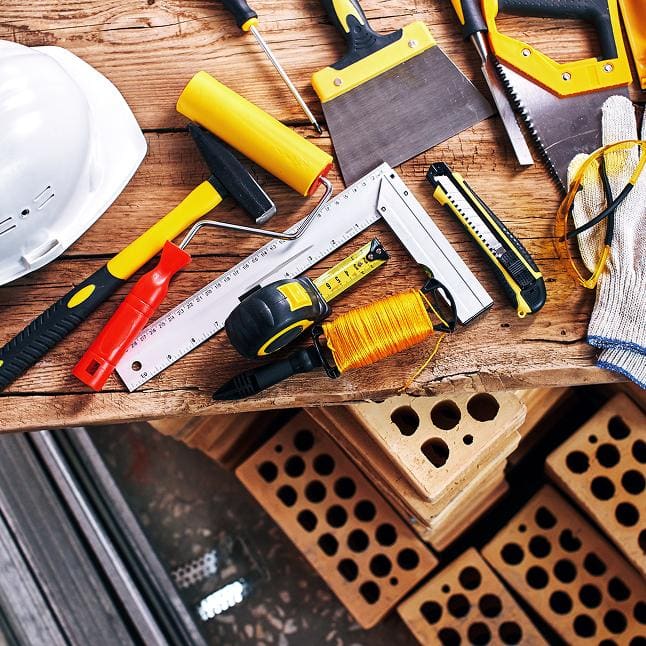 Hard hat, hammer, tape measure, and carpentry tools laid out on a wooden workbench